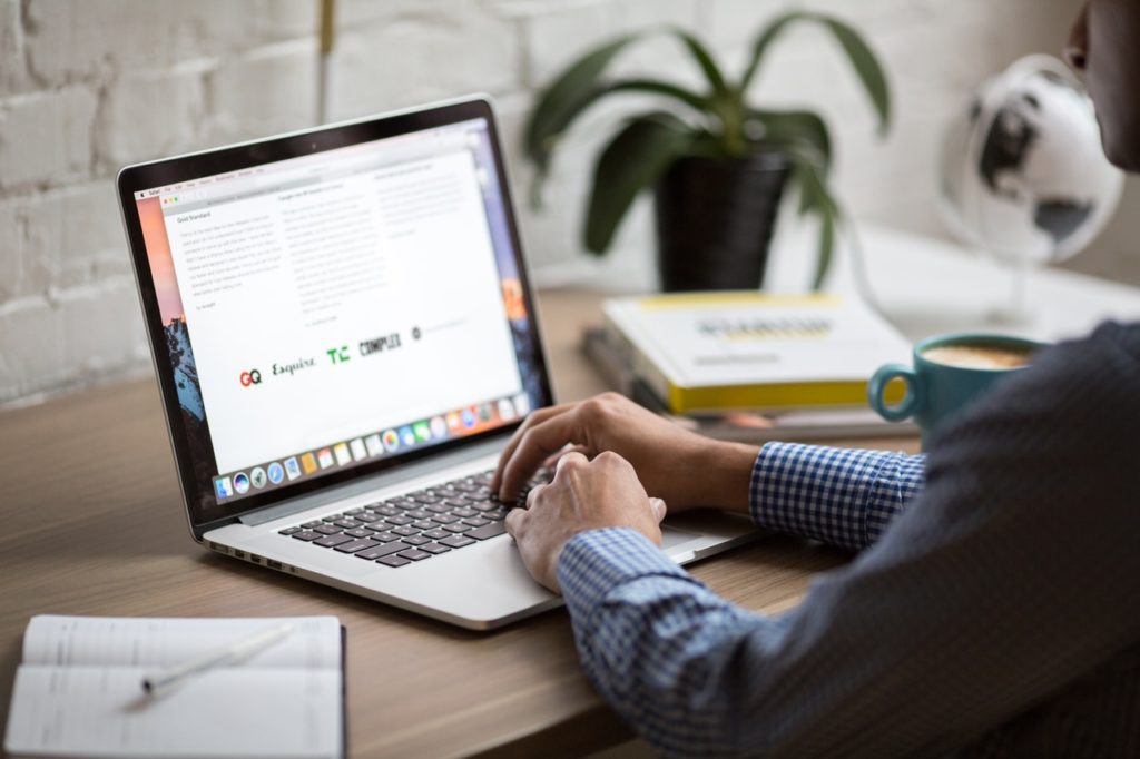 Man viewed from back writing an email on their laptop