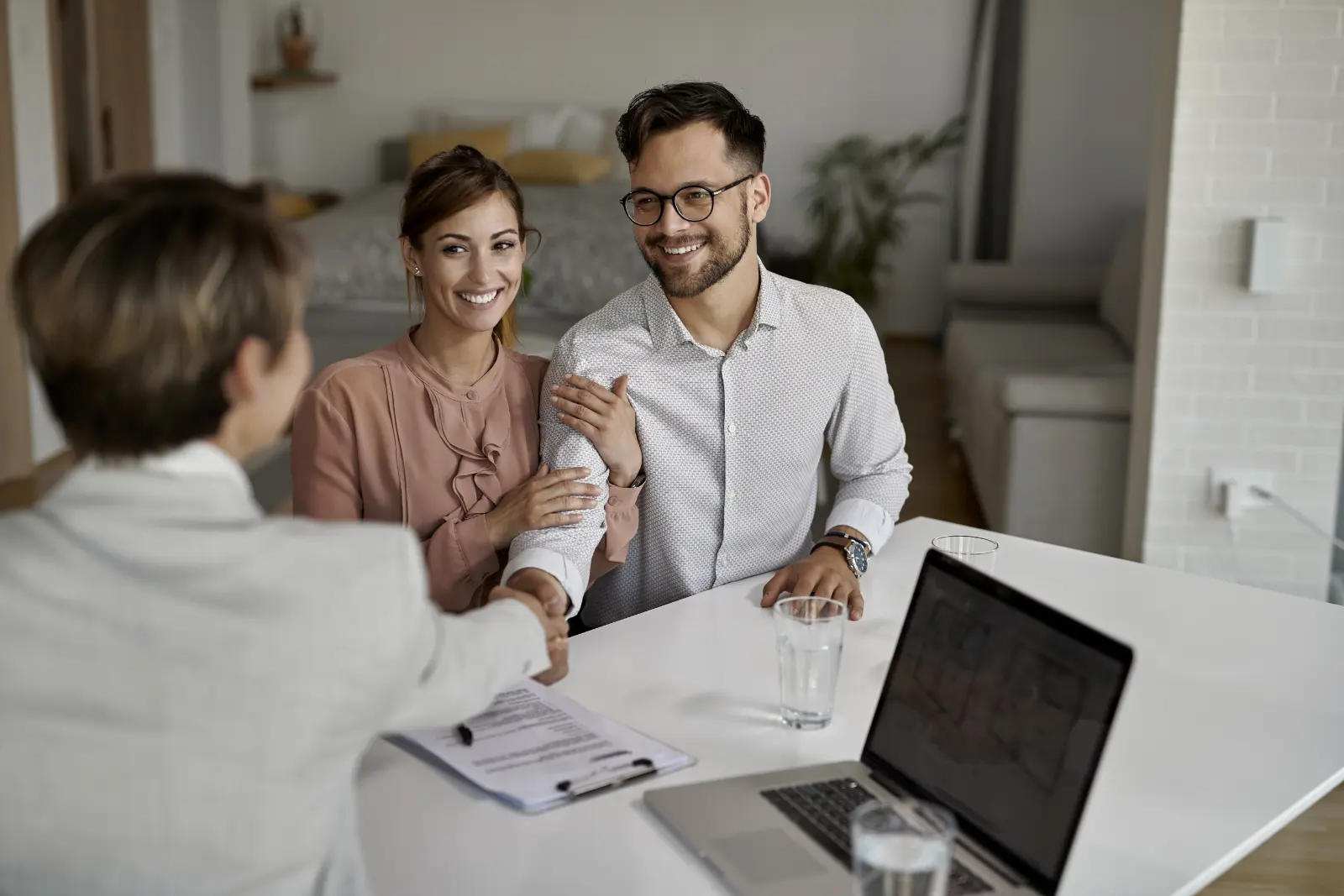 real estate agent shaking hands with a happy couple in an office