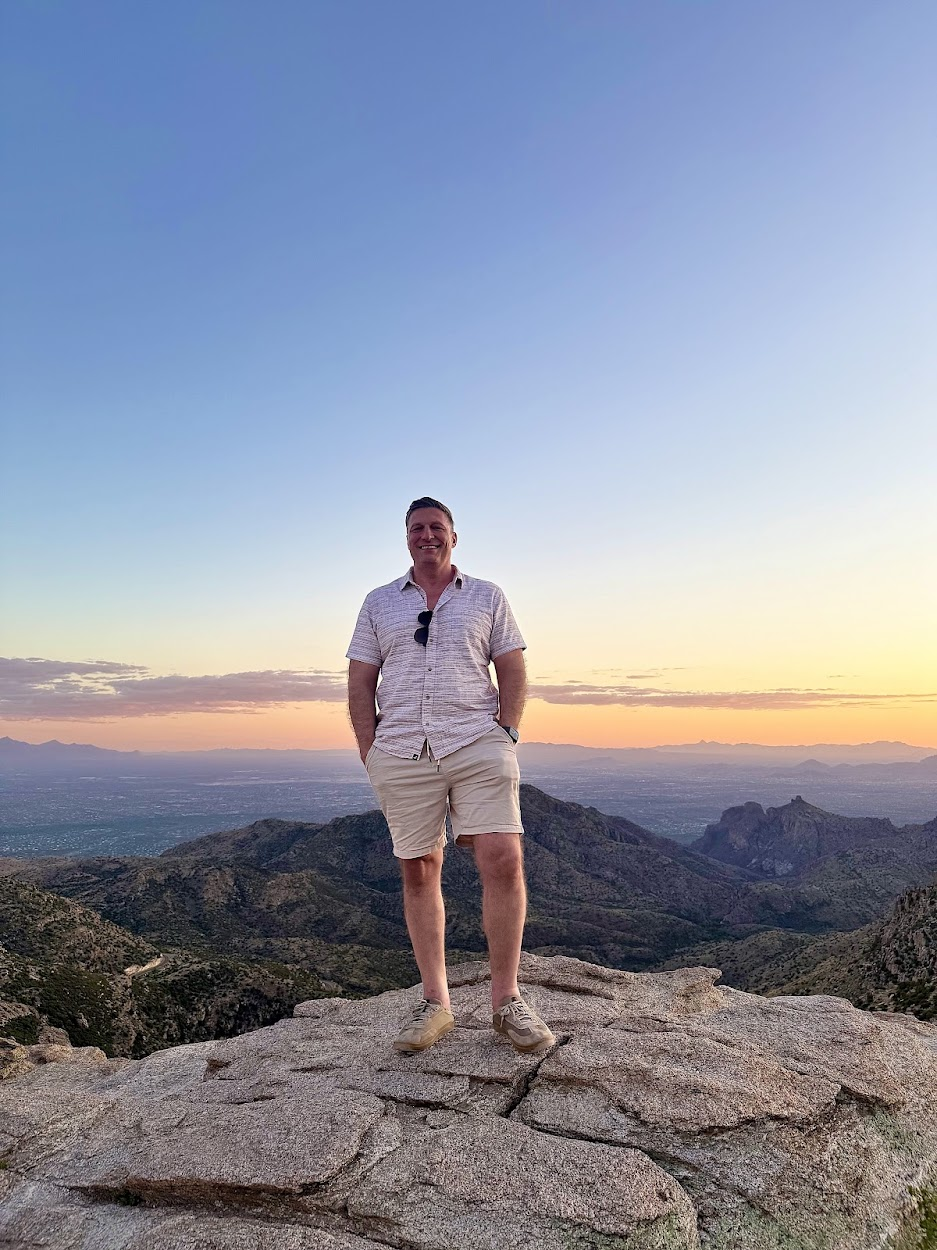 Jason Fox standing on a Tucson mountaintop at sunset